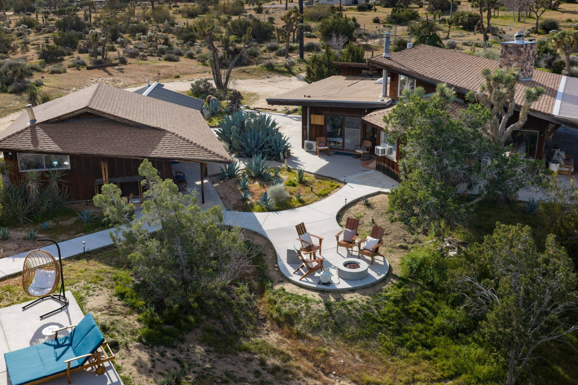 Covered wooden patio with lounge seating overlooking the Joshua Tree desert at golden hour